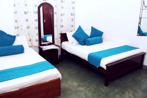 a room with two beds with blue pillows at Bethel Rest Homestay in Kandy