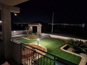 einen Balkon mit einem Garten voller Gras in der Nacht in der Unterkunft Apartman Sipina 3 in Kukljica
