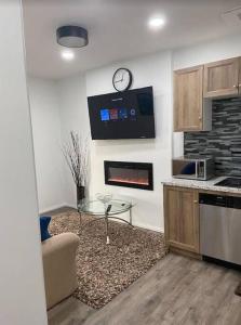 a living room with a fireplace and a clock on the wall at Walk 2mins to Shopping & Bussing,1-Bed Room Suite in Fort McMurray