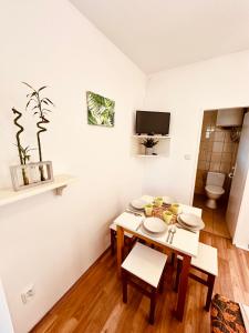 Cette petite chambre blanche dispose d'une table et de chaises. dans l'établissement Bamboo Rooms, à Štúrovo