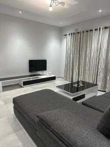 sala de estar con cama y TV de pantalla plana en Mountain Drive Apartments en Mbabane