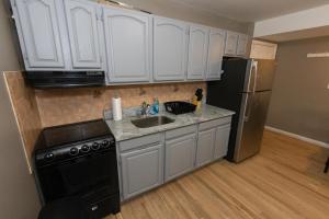 a kitchen with white cabinets and a sink and a refrigerator at Mins to NYC! Urban Oasis 2-BR home with King & Queen Beds in Jersey City