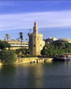 Ritual Sevilla, Fedriani في إشبيلية: مبنى فيه برج ساعه بجانب تجمع المياه