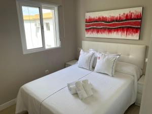 una camera da letto con un letto bianco con due asciugamani di Ritual Sevilla, Fedriani a Siviglia