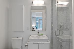 a white bathroom with a sink and a shower at Downtown Apartments 18 in Toronto