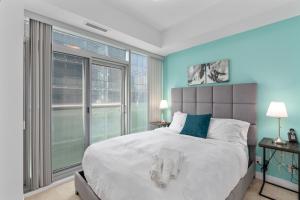 a bedroom with a large bed with blue walls and windows at Downtown Apartments 18 in Toronto