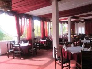 une salle à manger avec des tables, des chaises et des rideaux rouges dans l'établissement Hôtel El Ayachi, à Midelt