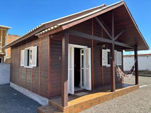 a small wooden building with a open door at Chalé de 1 quarto, com estacionamento, a 5 min da praia! in Passo de Torres