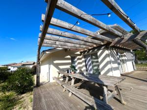 a wooden picnic table on a wooden deck at VILLA SOWA - Maison avec piscine 850m océan in Mimizan