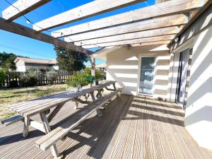 a picnic table on the deck of a house at VILLA SOWA - Maison avec piscine 850m océan in Mimizan
