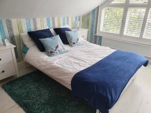 a bed with blue and white sheets and pillows at Bournemouth secluded cottage 10mins walk to beach in Bournemouth