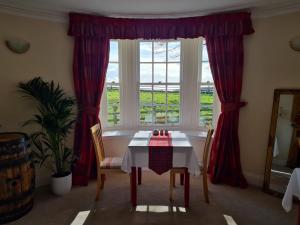 a dining room with a table and a window at Tarrel Farmhouse in Portmahomack