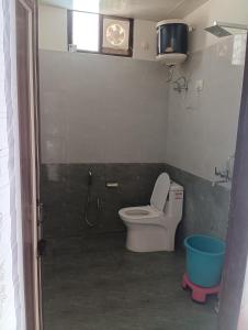 ein Badezimmer mit einem WC und einer Uhr an der Wand in der Unterkunft Sadhna Holiday Home in Bhowāli