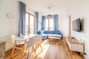 salon z niebieską kanapą i stołem w obiekcie 3L Apartments Olympic Park w Kołobrzegu