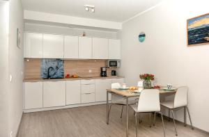 a kitchen with white cabinets and a table and chairs at Grunwaldzka 12 A4 Easy-Rent Apartments - 50m od plaży z dużym tarasem in Pobierowo