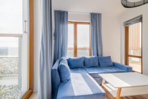 niebieska kanapa w salonie z oknem w obiekcie 3L Apartments Olympic Park w Kołobrzegu