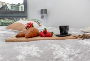 a wooden cutting board with strawberries and croissants on a bed at Grunwaldzka 12 A4 Easy-Rent Apartments - 50m od plaży z dużym tarasem in Pobierowo