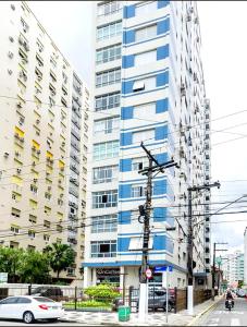 un edificio alto azul y blanco en una calle de la ciudad en Santos Gonzaga - Vista mar & localização perfeita, en Santos