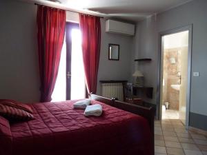Un dormitorio con una cama con sábanas rojas y una ventana en Agriturismo Viticcio, en La Morra