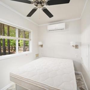 um quarto branco com uma cama e uma ventoinha de tecto em Jellystone Park Birchwood Acres em Greenfield Park