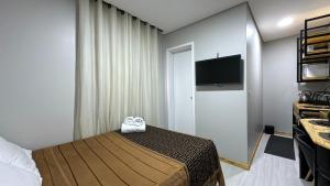 a bedroom with a bed and a flat screen tv at 21- Studio com decoração linda in Curitiba