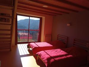two beds in a room with a large window at Gîte de la Borie de Pourtou in Condat