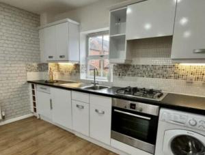 a kitchen with white cabinets and a sink and a stove at Cathedral Walk 3 Bed Coachhouse in Lichfield
