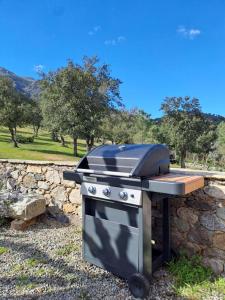 einem Grill neben einer Steinmauer in der Unterkunft Maison en pierre corse avec vue entre mer et montagne in Moltifao