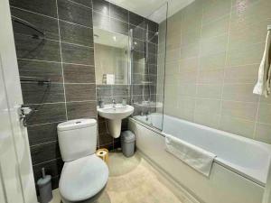 a bathroom with a toilet and a sink and a tub at Folkestone 3 Bedroom Home just off M20, great area in Kent