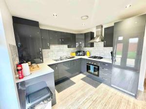 a large kitchen with black cabinets and stainless steel appliances at Folkestone 3 Bedroom Home just off M20, great area in Kent