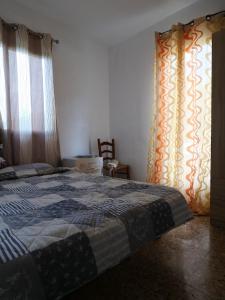 a bedroom with a bed and a window with curtains at Finca Caracol in Bolulla
