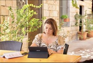 Villa Mira Guesthouse - Downtown Central Amman - AL DIYRIH في عمّان: امرأة تجلس على طاولة باستخدام الكمبيوتر المحمول