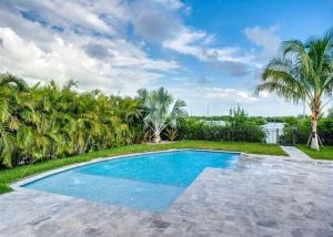 a swimming pool in a yard with palm trees at Modern Keys by Brightwild-Waterfront w Dock in Key West