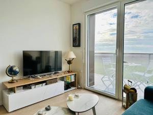ein Wohnzimmer mit einem TV und einem großen Fenster in der Unterkunft Face à la mer immense in Cayeux-sur-Mer