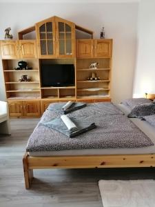 1 dormitorio con 1 cama, TV y armarios de madera en Őrségi Lápréti Vendégház, en Szőce