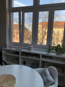 a living room with three windows and a white couch at Studio apartman Park Galerija in Osijek