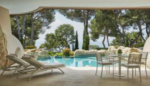 a patio with a table and chairs next to a pool at Grand-Hôtel du Cap-Ferrat, A Four Seasons Hotel in Saint-Jean-Cap-Ferrat