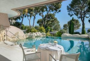 a dining room with a table and chairs next to a pool at Grand-Hôtel du Cap-Ferrat, A Four Seasons Hotel in Saint-Jean-Cap-Ferrat