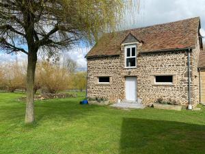 ein Backsteinhaus mit einer weißen Tür und einem Baum in der Unterkunft Le Petitepinay in Moitron-sur-Sarthe