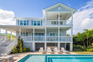 a white house with a swimming pool in front of it at Coastal Bliss by Brightwild-Pool, Parking, Dock! in Key West