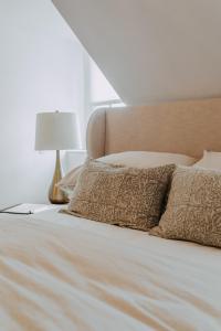 łóżko z białą pościelą i poduszkami oraz lampą w obiekcie No. 5 East w mieście Winnipeg