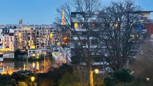a view of a city at night with buildings at Sweet home near Paris with Eiffel Tower view & 1 cozy private room or entire apartment with 3 rooms in Courbevoie