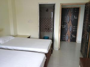 two beds in a room with a door and a room with at Budha ashram guest house in Bodh Gaya