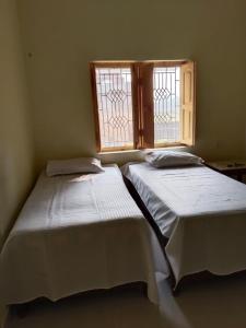 two beds in a room with two windows at Budha ashram guest house in Bodh Gaya