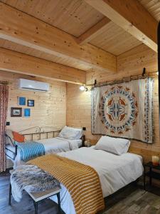 two beds in a room with wooden walls at Bosquey Ranch B&B in Alice Castello