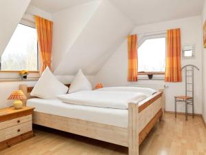 Schlafzimmer mit einem Bett mit weißer Bettwäsche und orangefarbenen Vorhängen in der Unterkunft Landhaus Residenz Ostsee Meeresbrise in Insel Poel