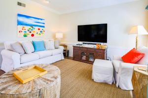 sala de estar con muebles blancos y TV de pantalla plana en Coastal Chic, en Isle of Palms