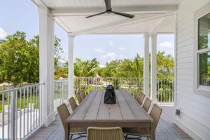 a wooden table on a porch with chairs and a ceiling fan at The Crestwood House - Private Heated Pool & Parking in Key West