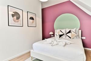 a bedroom with a white bed with a pink wall at Appartement spacieux à 5 minutes de la capitale in Bagnolet