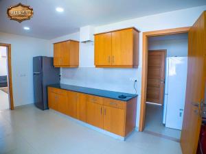 a kitchen with wooden cabinets and a black refrigerator at Villa 23 in Islamabad